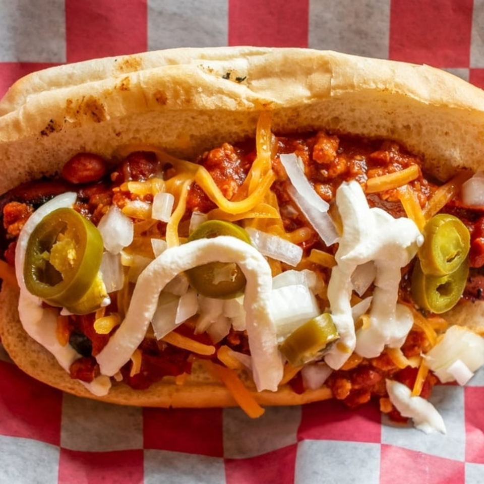 A chili dog from The Little Russia Chili Parlor, topped with cheese, onions, jalapeños, and sour cream.